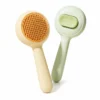 Round self-cleaning slicker brush for cats and dogs shown from front and back.