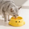 Grey cat drinking water from a yellow seal-shaped cat bowl